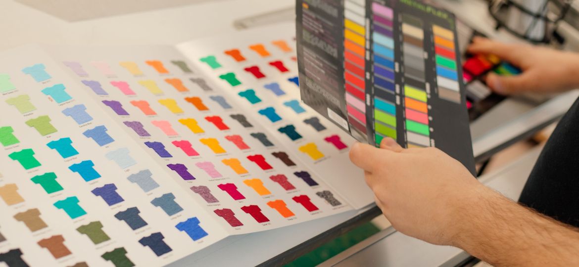 Cropped man hands choosing samples catalog palette rack color advertising T-shirts palette film membrane. Close up